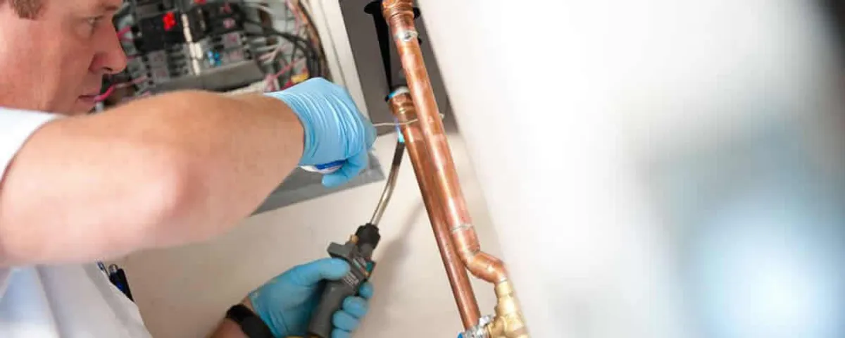 Water heater repair technician testing copper pipe connections and controls in Knoxville, TN